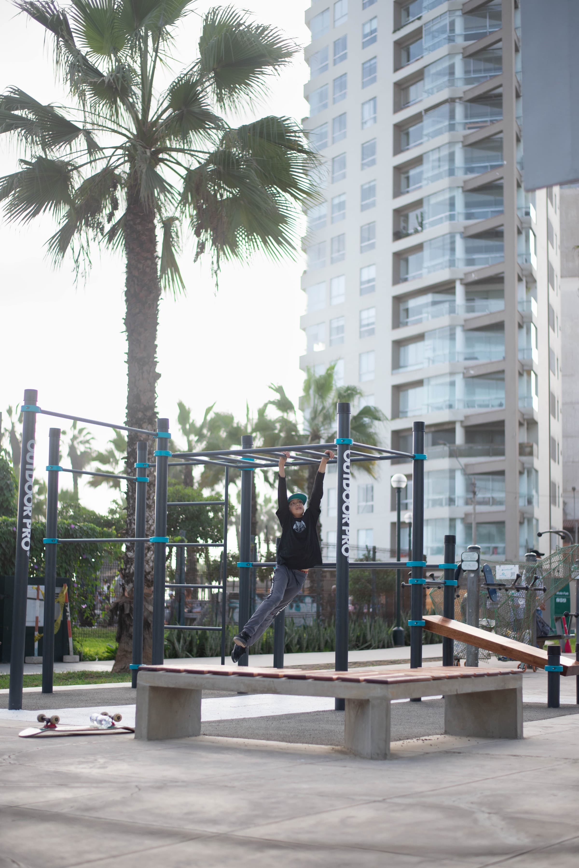 Niño colgado de las barras del módulo de calistenia del Skatepark de Miraflores